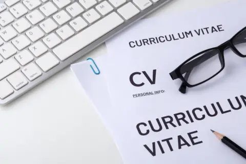 Klawiatura, okulary i dokumenty CV na białym tle.