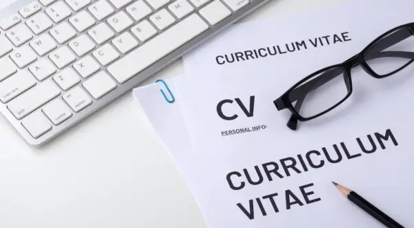 Klawiatura, okulary i dokumenty CV na białym tle.