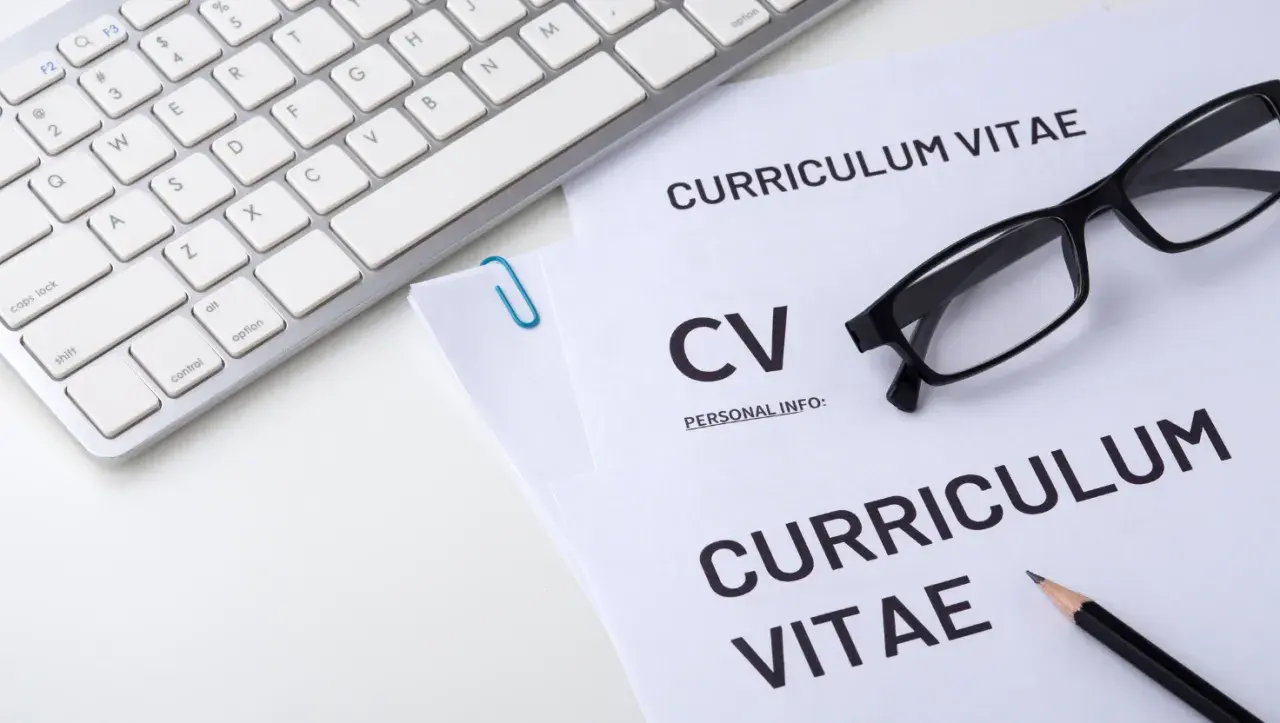 Klawiatura, okulary i dokumenty CV na białym tle.