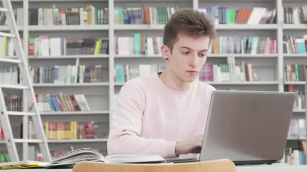 Osoba studiująca z książkami i laptopem, zdeterminowana
